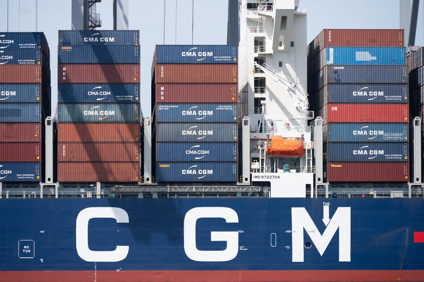 Cargo ship with stacked containers and "c g m" branding
